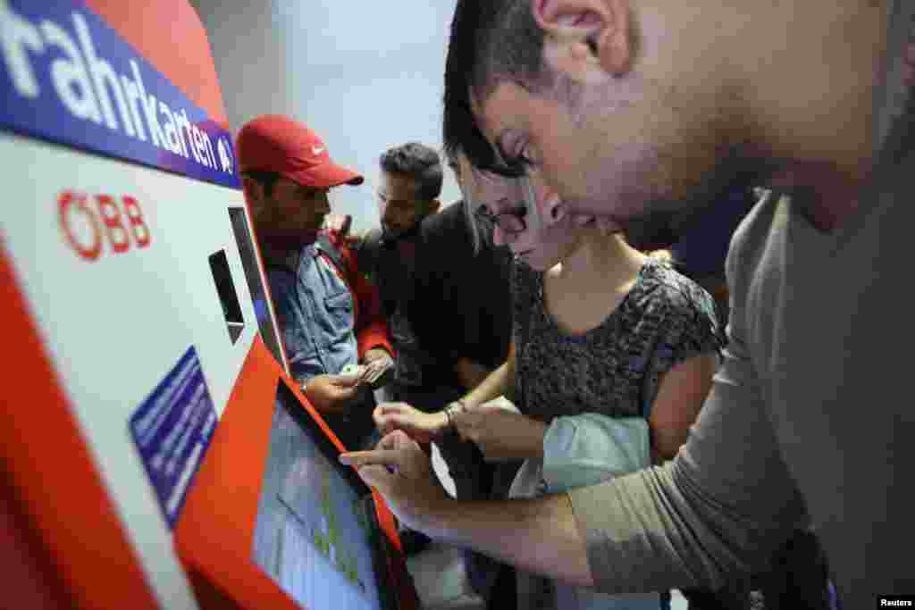 A local woman helps a migrant to buy a ticket for a train towards Garaz at the Austria-Slovenia border train station in Spielfeld, Austria.