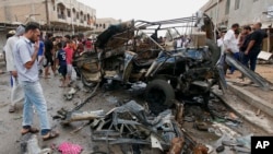 Civilians gather at the scene of a car bomb attack in Kamaliyah neighborhood, a predominantly Shiite area of eastern Baghdad, Iraq, Monday, May 20, 2013.