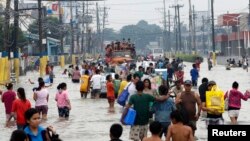 Residents wade through floodwaters on a street in Bacoor, Cavite near Manila, August 20, 2013. 