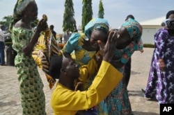 FILE - Family members celebrate as they embrace a relative, one of the released kidnapped schoolgirls, in Abuja, Nigeria, May 20, 2017. ﻿The 82 Nigerian schoolgirls recently released after more than three years in Boko Haram captivity reunited with their families.