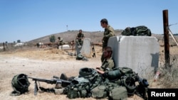 Tentara Israel tampak beristirahat di dekat gerbang di wilayah Dataran Tinggi Golan yang berlokasi di dekat perbatasan Israel dan Suriah, pada 3 Agustus 2020. (Foto: Reuters/Ronen Zvulun)