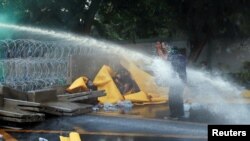 Seorang demonstran melindungi dirinya dari water canon selama protes anti-pemerintah ketika anggota parlemen berdebat tentang perubahan konstitusi, di luar gedung parlemen di Bangkok, Thailand, 17 November 2020. (Foto: Reuters)