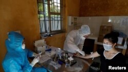 Medical specialists wearing protective suits collect blood sample from a woman who has returned after travelling to Da Nang, where new outbreak was first reported on July 25, and has spread to major urban centers.