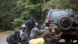 Membros das forças de segurança e jornalistas escondem-se atras de um veiculo durante troca de tiros no centro comercial Westgate (Nairobi, Setembro 2013)