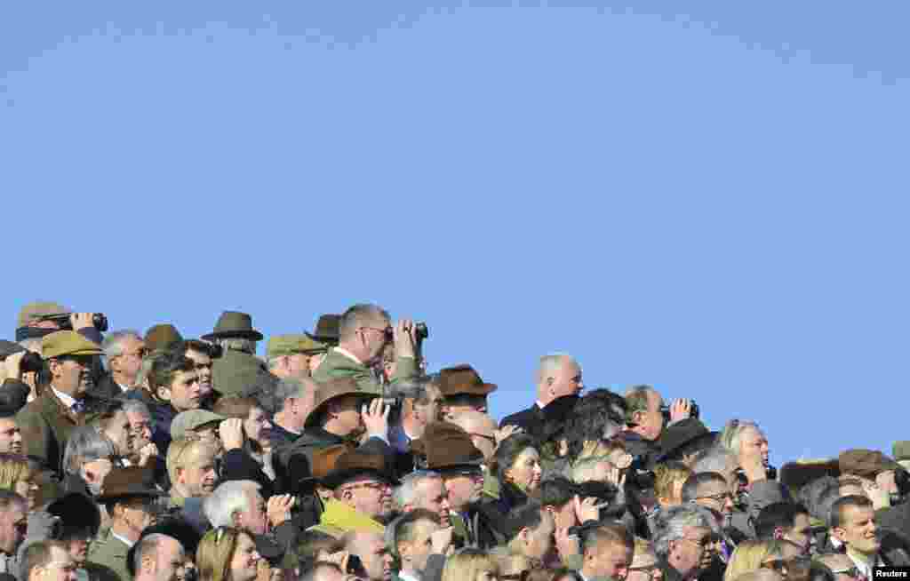 Racegoers watch on the first day of the Cheltenham Festival horse racing in Gloucestershire, western England.