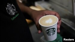 An employee prepares a coffee drink at a Starbucks' outlet at a market in New Delhi