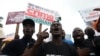 Des manifestants se rassemblent avec des pancartes à la main, lors d'une manifestation pour commémorer le premier anniversaire d'EndSars, un mouvement de protestation contre la brutalité policière à la fontaine de l'Unité à Abuja, le 20 octobre 2021.