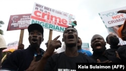Des manifestants se rassemblent avec des pancartes à la main, lors d'une manifestation pour commémorer le premier anniversaire d'EndSars, un mouvement de protestation contre la brutalité policière à la fontaine de l'Unité à Abuja, le 20 octobre 2021.