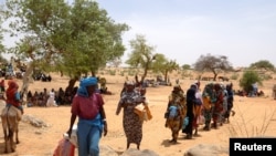 FILE: Halime Adam Moussa, a Sudanese refugee who has fled the violence in her country for the second time, walks in line to receive her food portion from World Food Programme (WFP), near the border between Sudan and Chad in Koufroun, Chad, on May 9, 2023.