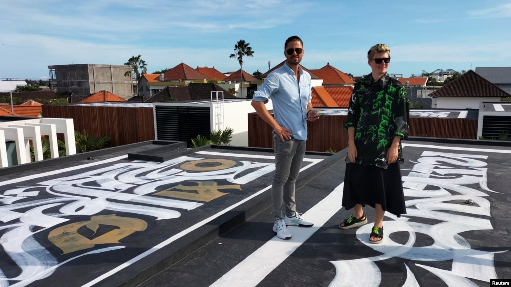 Russian artist Pokras Lampas and Ukrainian Alex Shtefan stand with one of nine of Pokras' calligraphy artwork on top of Alex's getaway homes in Bali, Indonesia on March 16, 2022. (REUTERS/Sultan Anshori)