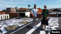 Russian artist Pokras Lampas and Ukrainian Alex Shtefan stand with one of nine of Pokras' calligraphy artwork on top of Alex's getaway homes in Bali, Indonesia on March 16, 2022. (REUTERS/Sultan Anshori)