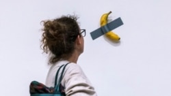 In this file photo, a woman looks at artist Maurizio Cattelan's piece of art "Comedian" during an auction preview at Sotheby's in New York, Monday, Nov. 11, 2024. (AP Photo/Eduardo Munoz Alvarez, File)