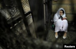 FILE - Aya Hijazi, founder of Belady, an NGO that promotes a better life for street children, sits reading a book inside a holding cell as she faces trial on charges of human trafficking at a courthouse in Cairo, Egypt, March 23, 2017.