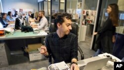 FILE - Mohammad Hazem Rezq, one of the Vogue staff works behind his desk at the magazine office at the Dubai Design District in Dubai, United Arab Emirates, Wednesday, March 15, 2017. 