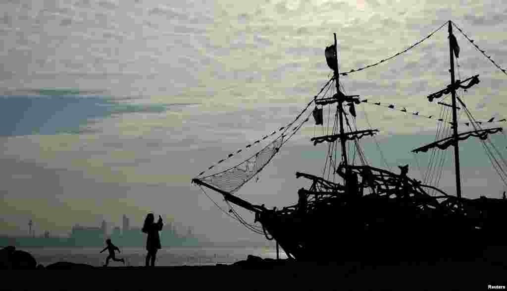 People play in front of a driftwood pirate ship on New Brighton beach near Wallasey, Britain.