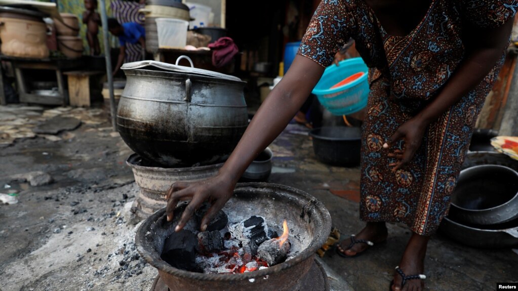 FILE - A woman arranges charcoal on an improvised cook stove in Ikeja, Lagos, Nigeria, Nov. 3, 2021.