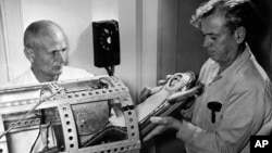 This NASA photo shows Dr. Hugh Blodgett (left) and Dr. Lynn Brown, both of the University of Texas, placing a monkey in a container during a pre-flight test. This actual launch was on December 4, 1959, at Wallops Island, Virginia. (AP Photo/NASA)