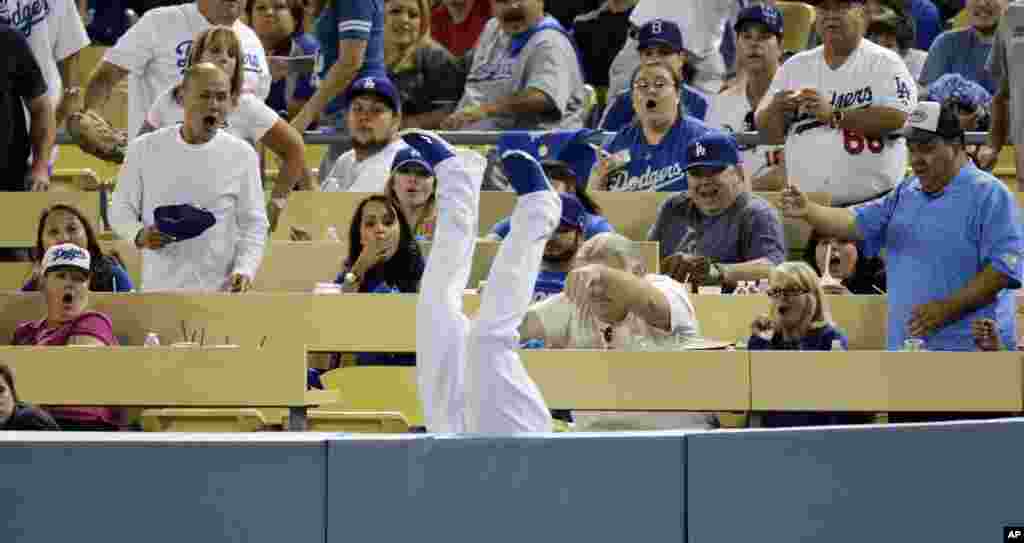 Fans react as Los Angeles Dodgers left fielder Carl Crawford falls upside down over the rail after catching a foul ball hit by Atlanta Braves' Justin Upton in Los Angeles, California, Oct. 6, 2013.