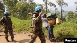 FILE - In this file photo, Indian soldiers, serving in the U.N. peacekeeping mission in DR Congo (MONUSCO), patrol past Congolese women walking to the market center in Masisi, northwest of Goma, Oct. 4, 2013.