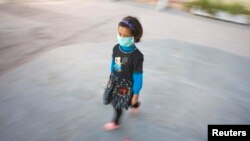 FILE - An Afghan girl wears a protective mask as she walks out of a school in Herat province, Nov. 3, 2009.