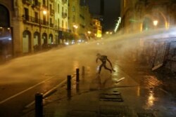 A demonstrator is hit by a water cannon during a protest against the ruling elite in Lebanon, in Beirut, Jan. 19, 2020.