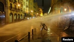 FILE - A demonstrator is hit by a water cannon during a protest against a ruling elite accused of steering Lebanon towards economic crisis, in Beirut, Lebanon, Jan. 19, 2020.