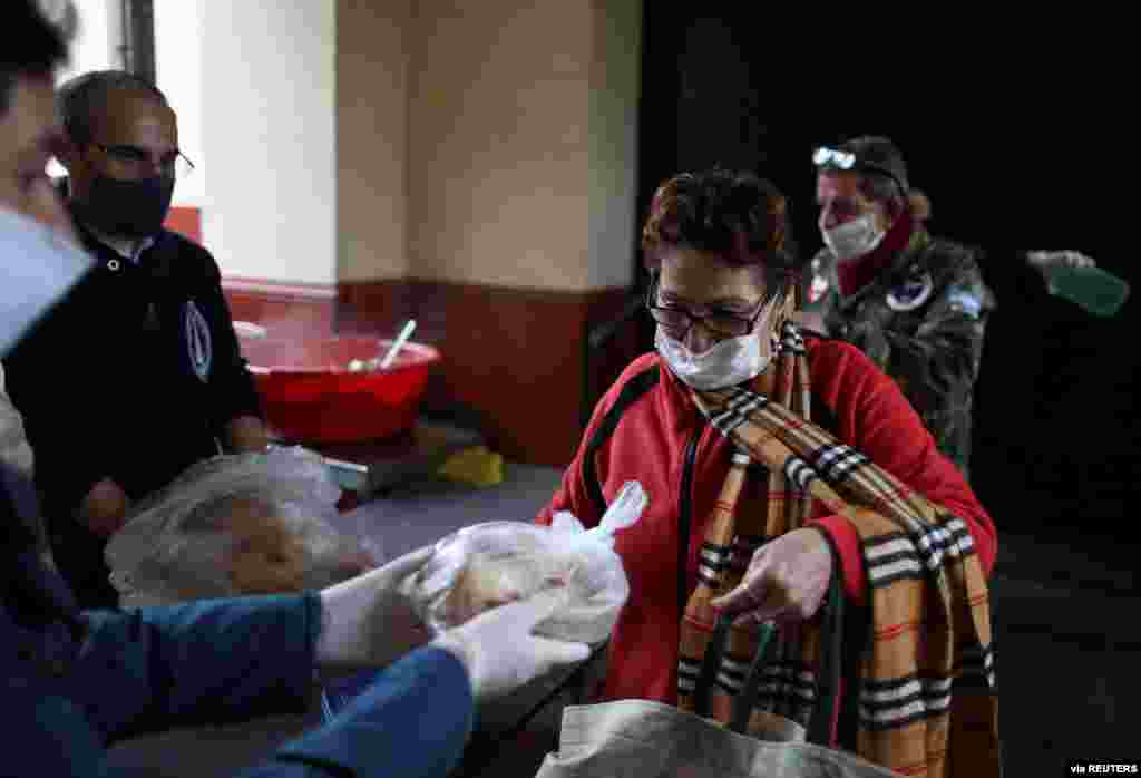 Durante estos tiempos de pandemia, muchas personas se han solidarizado con los m&#225;s necesitados, brindado alimentos. En esta imagen una se&#241;ora recibe pan frente a la Parroquia Nuestra Se&#241;ora de Caacup&#233;, en Buenos Aires, Aregentina.