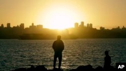 Two men watch as the sun sets over San Francisco from Yerba Buena Island, Jan. 5, 2016.