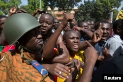 FILE - Anti-government protesters chant slogans in front of army headquarters in Ouagadougou, capital of Burkina Faso, Oct. 31, 2014.