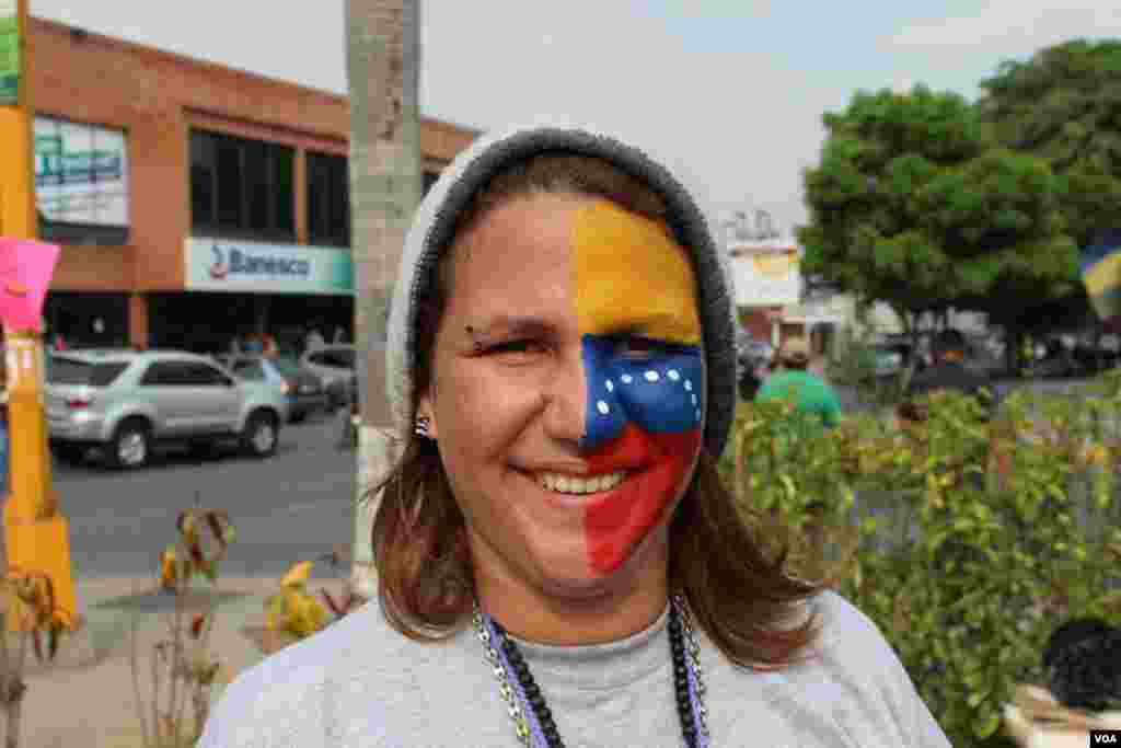 A woman paints her face with the Venezuelan flag.