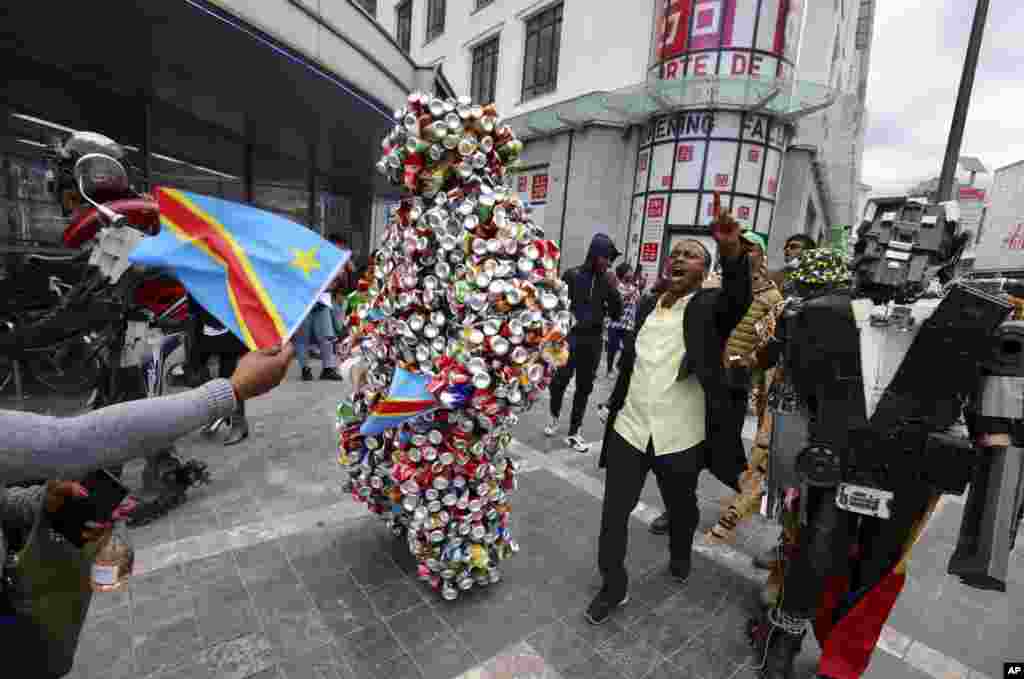 A man and two artists dressed in costume participate in celebrations marking the 60th anniversary of Congo&#39;s independence from Belgium in the Brussels district of Matonge.