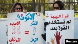 Women hold banners during a demonstration for women's rights in Tripoli. The poster on the left reads, "Quota: Since two women equal one man (in Sharia law), there should be two women for every man in parliament. Then the formula will be perfect." Feb. 7, 2013.