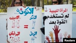 Dua perempuan memegang poster dalam sebuah unjuk rasa di Tripoli. Poster di kiri berbunyi: Karena dua perempuan sama dengan satu lelaki (dalam hukum Shariah), maka harus ada dua perempuan dalam setiap satu lelaki di parlemen, untuk membuat formula ini tepat (7/2/2012).