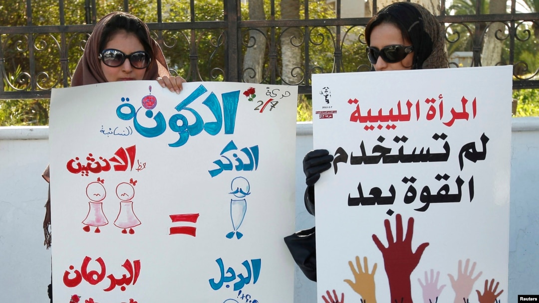 Women hold banners during a demonstration for women's rights in Tripoli. The poster on the left reads, "Quota: Since two women equal one man (in Sharia law), there should be two women for every man in parliament. Then the formula will be perfect." Feb. 7, 2013.