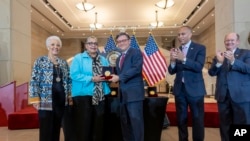 House Speaker Mike Johnson, center, presents a Congressional Gold Medal posthumously to Joylette Hylick, left, and Katherine Moore, daughters of Katherine Johnson at the Capitol in Washington, Sept. 18, 2024.