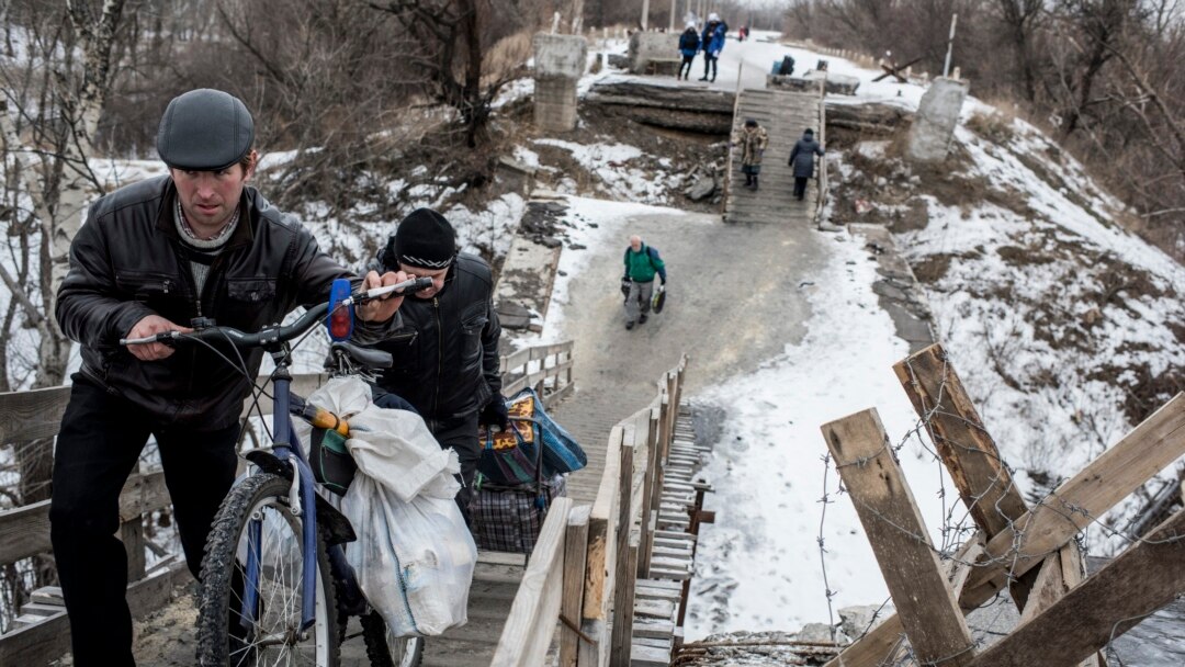 Local residents walk across a bridge damaged during fighting between Ukrainian government forces and Russia-backed rebels in Stanytsia Luhanska, Luhansk region, eastern Ukraine, Jan. 16, 2016.