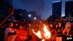 Protesters burn Myanmar flags during a demonstration against the military coup in Yangon on July 29, 2021. 