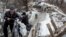FILE - Local residents walk across a bridge damaged during fighting between Ukrainian government forces and Russia-backed rebels in Stanytsia Luhanska, Luhansk region, eastern Ukraine, Jan. 16, 2016.