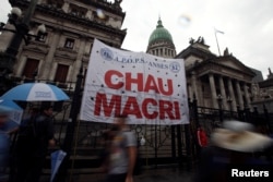 FILE - Argentine unions, small firms and activists gather outside Argentina's Congress to demand changes in President Mauricio Macri's economic policies, in Buenos Aires, Argentina, April 4, 2019. The banner reads "Bye Macri."