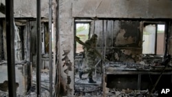 A pro-Russian rebel carries items seized from an Ukrainian border troops military unit in Luhansk, eastern Ukraine, June 4, 2014. 