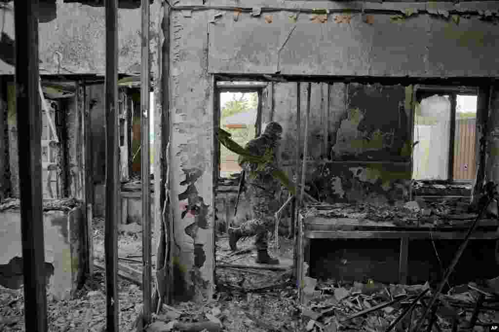 A pro-Russian rebel carries items seized from a Ukrainian border troops military unit in Luhansk, eastern Ukraine, June 4, 2014.