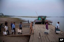 FILE—Election officers carry Electronic Voting Machines (EVM) on board a ferry to cross the Sowansiri river to reach a polling center on the eve OF elections in Majuli, India, March 26, 2021.