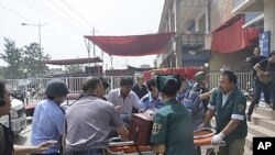 A handout picture shows rescuers carrying an injured victim on a stretcher out of a police station after a clash in Hotian, Xinjiang Uygur Autonomous Region, July 18, 2011