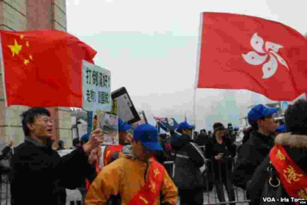 Pro-government and pro-Beijing activists hold a counter-demonstration on Canton Road, waving flags of China (left) and Hong Kong (right). One activist holds a sign saying, 'Down with traitors, dogs and betrayers of the country!' (Iris Tong, VOA)