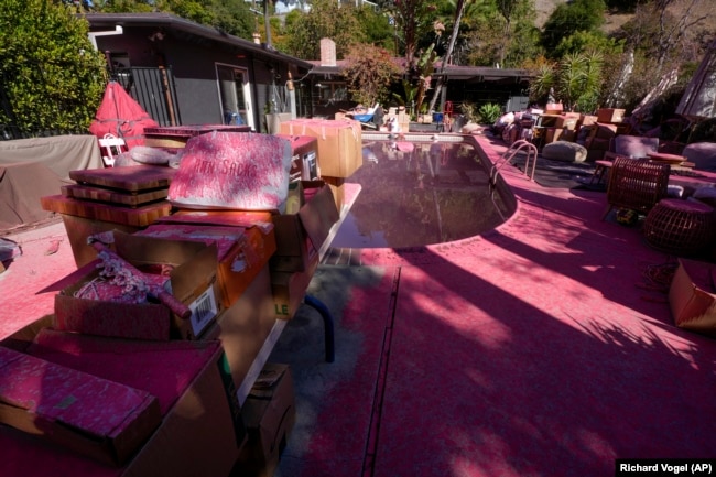 Retardant covers a backyard and pool after crews battled the Palisades Fire in Mandeville Canyon Monday, Jan. 13, 2025 in Los Angeles.