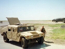 FILE - A U.S. soldier walks past a Humvee vehicle at the Karshi-Khanabad base, Uzbekistan, May 28, 2002.