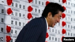 Japan's Prime Minister and leader of the ruling Liberal Democratic Party (LDP) Shinzo Abe smiles as he leaves an election campaign center at the LDP headquarters in Tokyo, July 21, 2013, after an upper house election. 