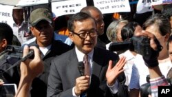 Opposition leader of Cambodia National Rescue Party Sam Rainsy, center, delivers a speech during a gathering to mark Human Rights Day, in front of National Assembly, in Phnom Penh, Cambodia, Wednesday, Dec. 10, 2014. (AP Photo/Heng Sinith)