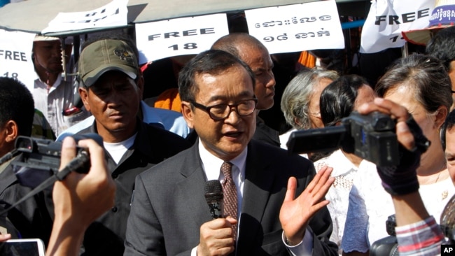 Opposition leader of Cambodia National Rescue Party Sam Rainsy, center, delivers a speech during a gathering to mark Human Rights Day, in front of National Assembly, in Phnom Penh, Cambodia, Wednesday, Dec. 10, 2014. (AP Photo/Heng Sinith)