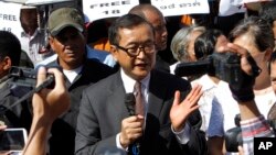 Opposition leader of Cambodia National Rescue Party Sam Rainsy, center, delivers a speech during a gathering to mark Human Rights Day, in front of National Assembly, in Phnom Penh, Cambodia, Wednesday, Dec. 10, 2014. (AP Photo/Heng Sinith)